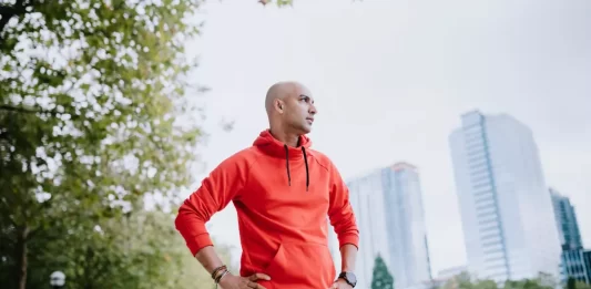 A person jogging in a park signifies exercise for belly fat reduction.