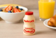 Yakult probiotic drink bottle on a table with a healthy breakfast background