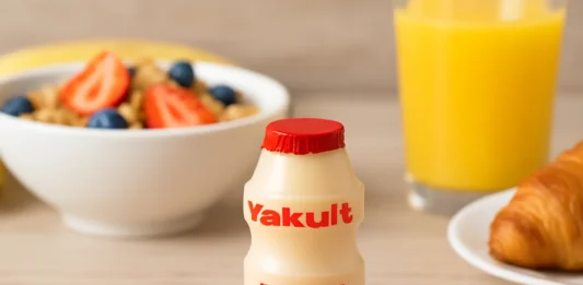 Yakult probiotic drink bottle on a table with a healthy breakfast background