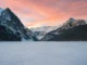 Snow-covered mountains and frozen Lake Louise in Banff National Park during winter.