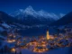 Snow-covered Austrian Alps with an alpine village illuminated during winter nights.