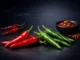 Vibrant red and green chili peppers on a dark gradient background, representing spicy foods and their potential health and longevity benefits.